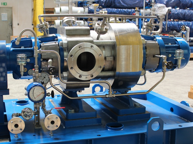 Apollo high-pressure pump type HP with axial inlet, metal housing, blue-painted pump base frame, and drive shaft contact protection. Two nanofiltration systems can be seen in the background.