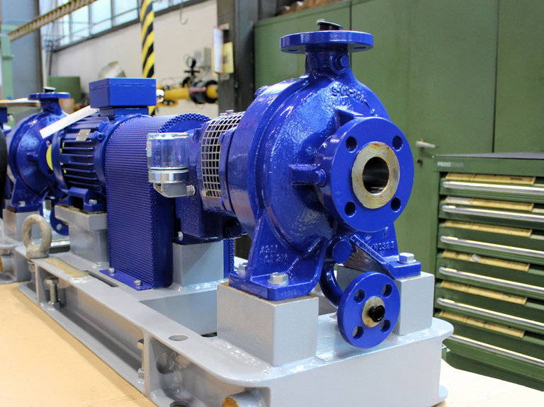 A KRC single-stage volute casing pump stands on an assembly table in Apollo's production hall. Green tool cabinets and a crane can be seen in the background.