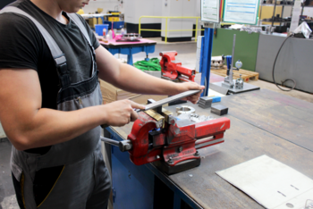 Auszubildender, der ein Werkstück aus Metall mit einem Metallpfeil bearbeitet