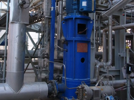 An Apollo vertical process pump type HPTV (VS6) is installed on a concrete foundation in a fertilizer plant with many pipes and lines for liquids and gases.