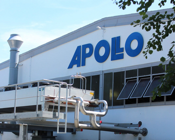 Apollo Logo an der Hallen Außenwand, im Vordergrund ist eine Hallenkühlung zusehen mit Lüftungen und am Bildrand ragt ein grün belaubter Ast ins Bild.