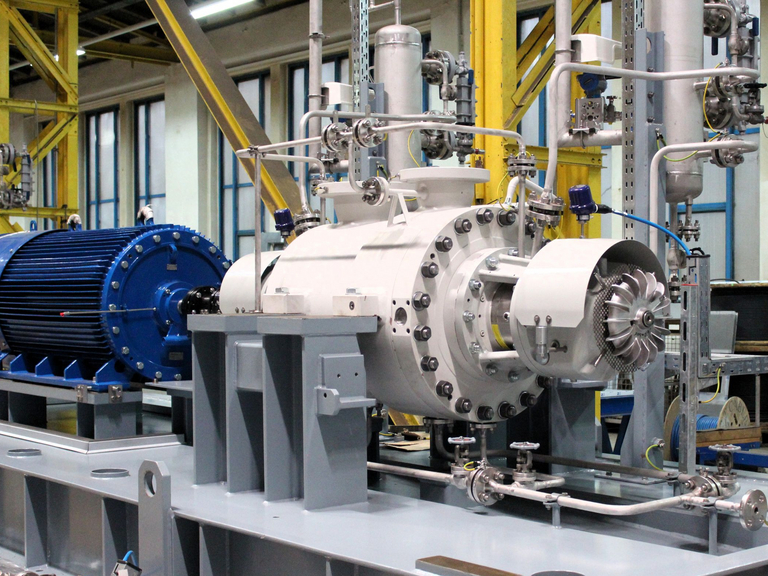 Seitliche Nahaufnahme auf ein BB5 mehrstufiges Barrelpumpenaggregat, welches in der Fertigungshalle während der Montage platziert ist. Zu sehen ist der Elektromotor, Pumpengehäuse, Grundrahmen und Verrohrung zum TS-System.