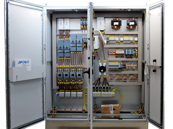 The image shows an Apollo control cabinet, a control cabinet for a pump system, in front view with open doors. The power and control components are visible, including frequency converters, fuse strips, and terminal strips, all of which are neatly structured and clearly labeled.
