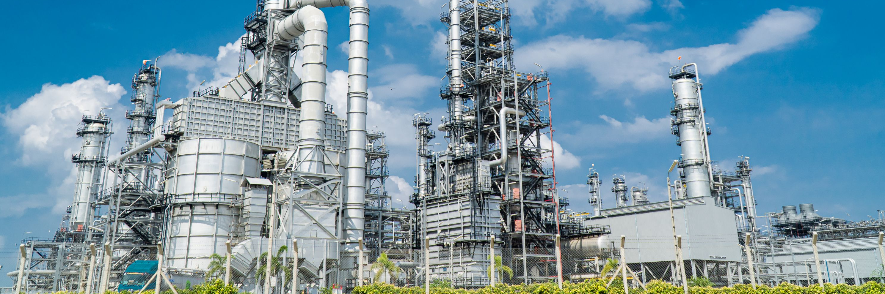 An industrial plant made of stainless steel, surrounded by green meadows and a slightly cloudy, blue sky.