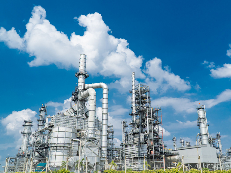 An industrial plant made of stainless steel, surrounded by green meadows and a slightly cloudy, blue sky.